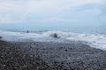 Waves on the seashore. Frothy waves. Clouds over the coast. The sea is stormy. The figure of a man, who wants to take a Royalty Free Stock Photo