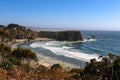 The tide rolls in to the shore around a bay and headland south of Mendicino California with defocused purple flowers in the foregr Royalty Free Stock Photo