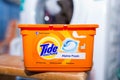 Tide washing liquid capsules in front of a washing machine.