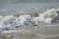 Tides of ocean water or sea water splashing onto the shore of a sandy beach causing white foam and bubbles