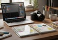 A tidy desk setup features a laptop displaying a digital design software interface, a Canon DSLR Royalty Free Stock Photo