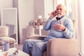 Tidy grey-haired senior answering urgent phone call