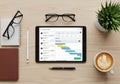 A tidy workspace with a digital tablet displaying a project management tool. Items include glasses, Royalty Free Stock Photo