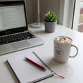 A tidy workspace features an open laptop displaying a web page, a spiral notebook