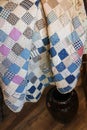 Tied antique quilt made of squares with brown crock on floor Royalty Free Stock Photo