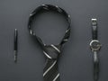 Tied black and white men`s tie, pen and watch on a black background Royalty Free Stock Photo