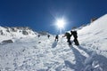 Tied climbers climbing mountain with snow field tied with a rope with ice axes and helmets