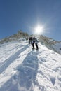 Tied climbers climbing mountain with snow field tied with crampons with ice axes and helmets