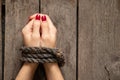 Tied female hands with rope on wooden background close-up Royalty Free Stock Photo