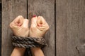 Tied female hands with rope on wooden background close-up Royalty Free Stock Photo