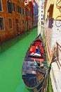 Tied gondola narrow canal aged houses Venice Italy