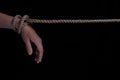 Tied hands with a rope on a black background. copy space for text