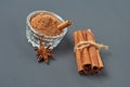 Tied pile of cinnamon sticks near glass bowl full of powder near star of anise lies on dark scratched desk on kitchen Royalty Free Stock Photo