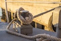 Tied rope knot on metallic bollard , seafaring port. Nautical ship moored in dock. Anchor rope in the port, ship mooring tool