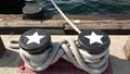 Tied rope knot on metallic bollard with stars, seafaring port of San Diego, California. Nautical ship moored in dock. Cable tie