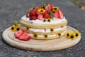 tiered layered cake with yellow wildflowers and strawberries wood board summer cake