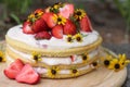 tiered layered cake with yellow wildflowers and strawberries wood board summer cake