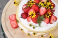 tiered layered cake with yellow wildflowers and strawberries wood board summer cake