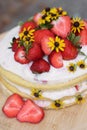 tiered layered cake with yellow wildflowers and strawberries wood board summer cake