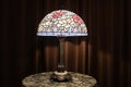 Tiffany lamp on a table that is lite up at night, the lamp is on, stained glass lamp shade