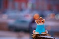 Tiger cub in a blue sweater on a stump in winter. Toy for the Christmas tree. Snowing. City street with transport in