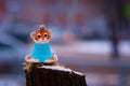 Tiger cub in a blue sweater on a stump in winter. Toy for the Christmas tree. Snowing. City street with transport in