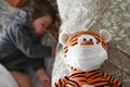 Tiger toy in white medical protective mask sitting near a sleeping baby. Child in home quarantine. Coronavirus concept Royalty Free Stock Photo