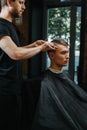 Tight-lipped male hairdresser making a haircut for a young man in a barber shop Royalty Free Stock Photo