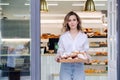 Tight lipped woman posing with a tray full of pastry in a doorstep of her shop Royalty Free Stock Photo