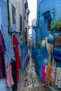 Tight and Narrow Blue Street in the Medina of Chefchaouen Morocco with Clothing for Sale Royalty Free Stock Photo