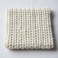 A tightly knitted square of chunky cream colored yarn on a white surface Royalty Free Stock Photo