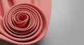 Tightly rolled pink fabric arranged in a spiral pattern on a smooth, light gray surfa Royalty Free Stock Photo