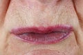 Tightly squeezed narrow pink lips of an elderly woman. The pores and skin defects are clearly visible