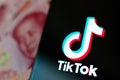 TikTok app logo on the smartphone screen and Chinese money next to it. TikTok US sold to Oracle and Walmart Royalty Free Stock Photo