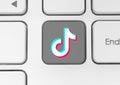 TikTok icon key on white computer keyboard close-up. Concept of working process in popular social media services. TikTok is a Royalty Free Stock Photo