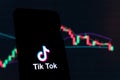 TikTok logo on mobile in front of a screen that shows stocks