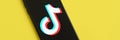 Tiktok logo on samsung smartphone screen on yellow background. TikTok is a popular video-sharing social networking service owned Royalty Free Stock Photo