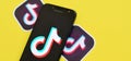 Tiktok logo on samsung smartphone screen on yellow background. TikTok is a popular video-sharing social networking service owned Royalty Free Stock Photo