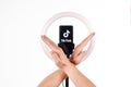 The tiktok logo on a smartphone attached to a round lamp with a tripod and male hands show the ban. Donald Trump to ban Tiktok in