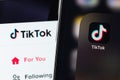 TikTok mobile app on screen smartphone iPhone with display notebook closeup