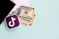 Tiktok paper logo lies with envelope full of dollar bills and smartphone