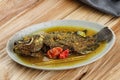 Tilapia Pesmol in a Oval Plate. Pesmol is a Sundanese Yellow Curry Spice Dish