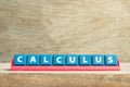 Tile letter on rack in word calculus on wood background