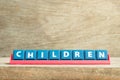 Tile letter on rack in word children on wood background