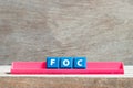 Tile letter on rack in word FOC Abbreviation of Free of charge on wood background