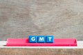 Tile letter on rack in word GMT abbreviation of Greenwich Mean Time on wood background