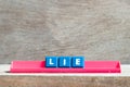 Tile letter on rack in word lie on wood background