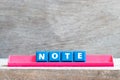 Tile letter on rack in word note on wood background