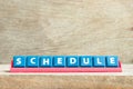 Tile letter on rack in word schedule on wood background