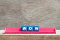 Tile letter on rack in word wow on wood background